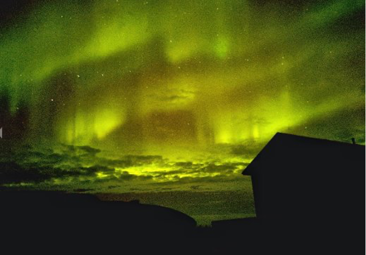 شفق قطبی یا شفق شمالی، آسمان شب را در بالای شبح یک خانه پر می کند.
