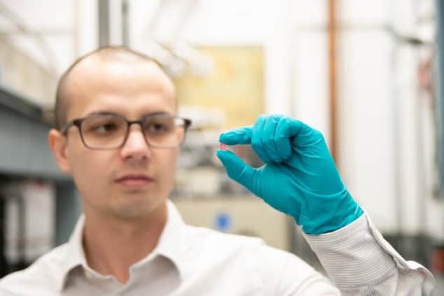 Christopher Simon sostiene un cristal de fluoruro de litio, holmio ytrio en su mano enguantada